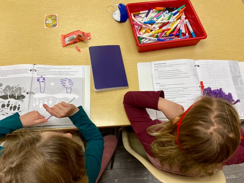 Two young girls doing activities from the Kids Celebrate booklets