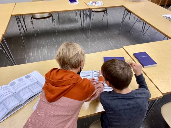 Two young boys work together on an activity in a Kids Celebrate booklet